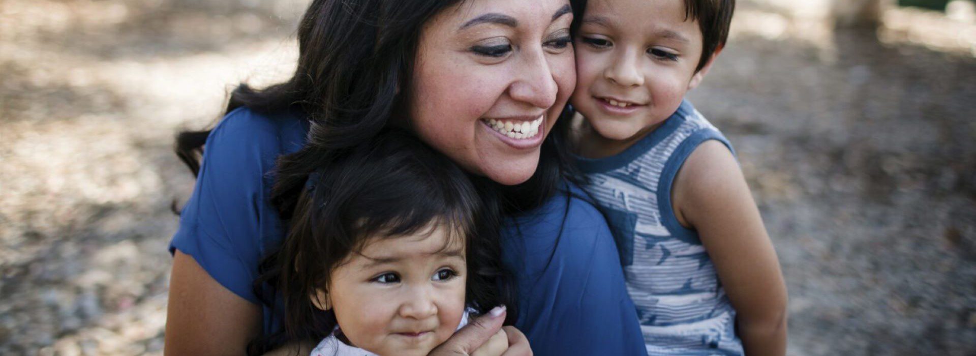 Mother hugging two small children